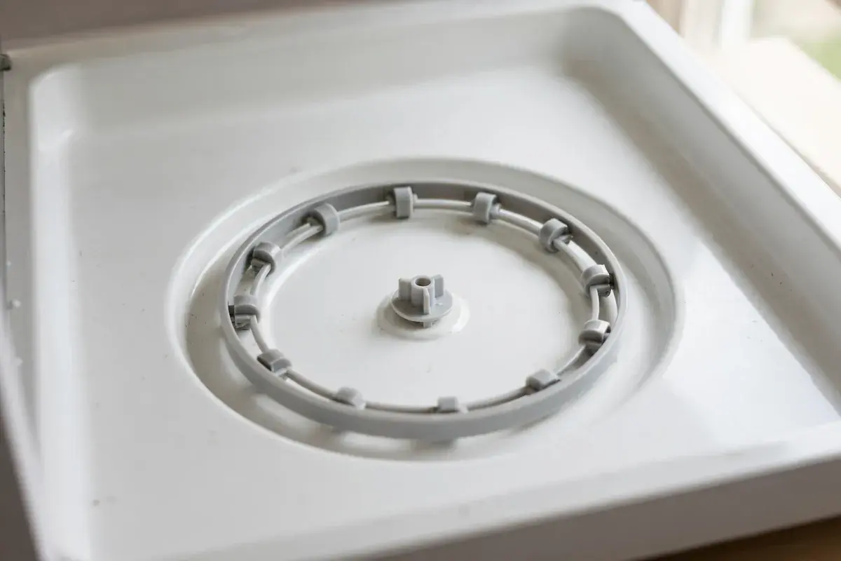 Microwave interior with the turntable plate lifted out beside the roller ring