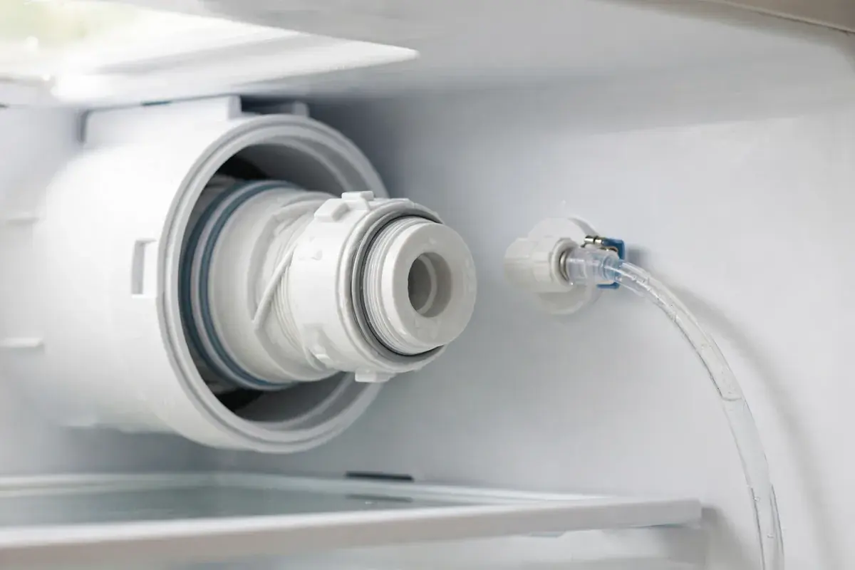 Refrigerator water filter cartridge partly removed from its housing